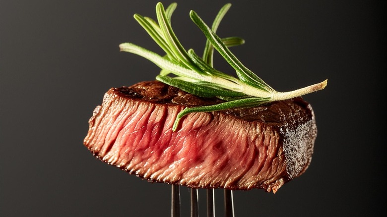 fork of steak with fresh rosemary on top