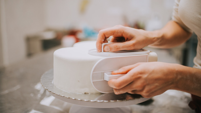 baker putting fondant on a cake