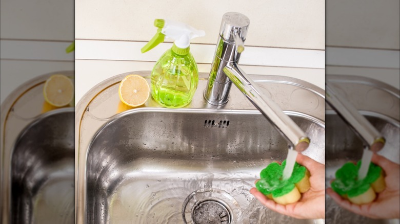 a person using a scrub to clean a stainless steel kitchen sink with lemon