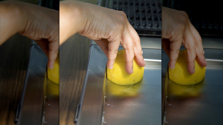 a person using a lemon half to clean stainless steel