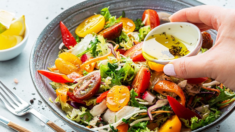 Pouring salad dressing on a salad