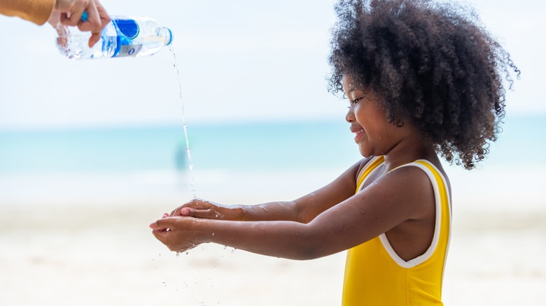 little girl washing hands at beach