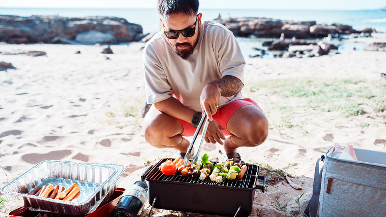 man grilling at beach