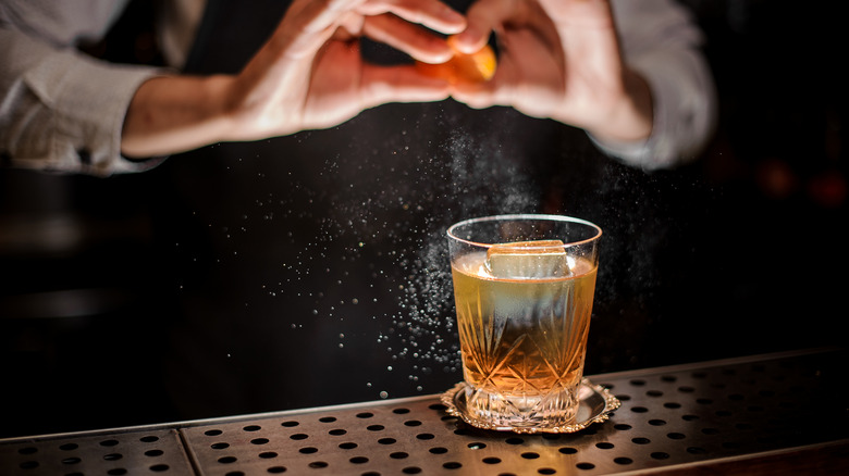 Bartender expressing citrus over cocktail