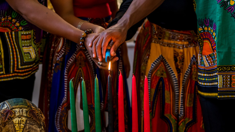 Hands lighting Kwanzaa candles