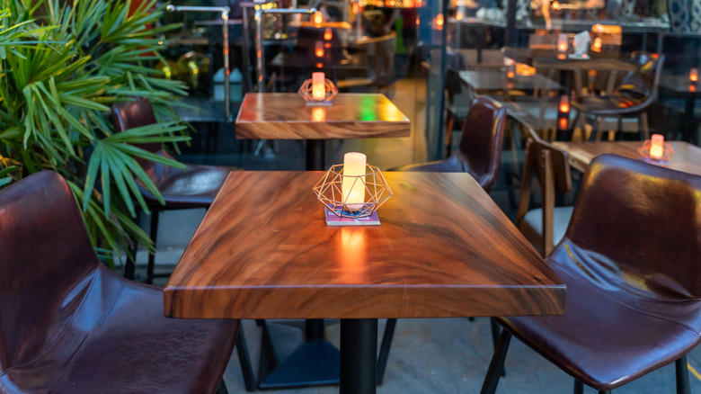 Empty wooden dining tables in a modern restaurant with leather chairs