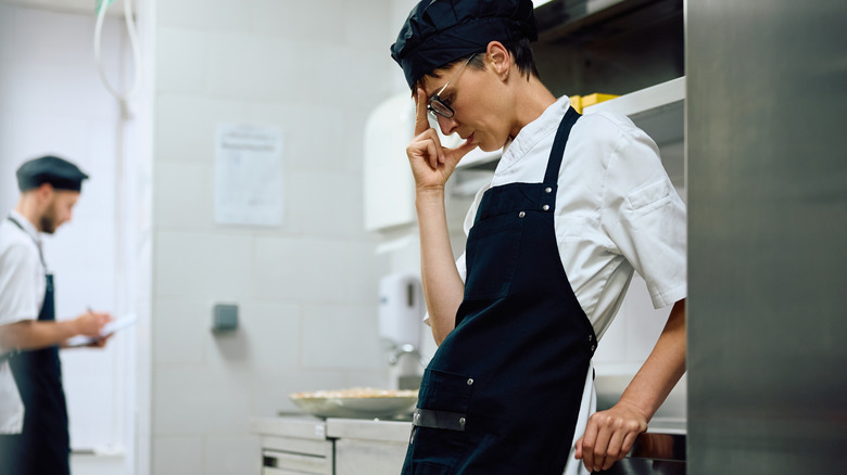 Female chef looking stressed out while working in a restaurant.