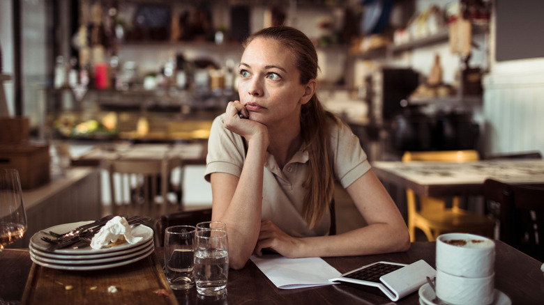 Waitress looking stressed while sitting at a restaurant table.