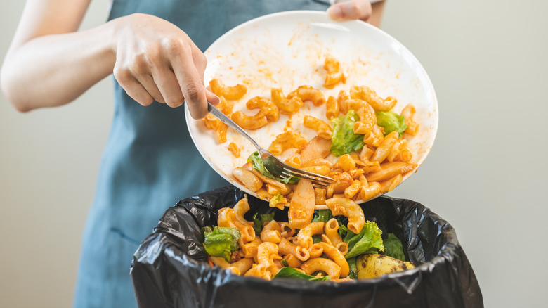 Scraping leftover food from plate into trash