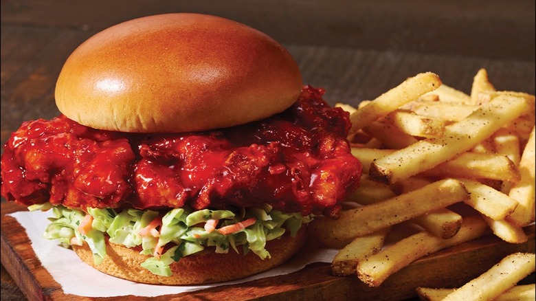 Applebee's sweet and spicy chicken sandwich with fries on wooden surface