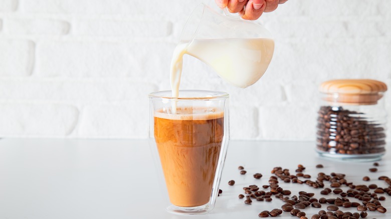 pouring milk into coffee glass