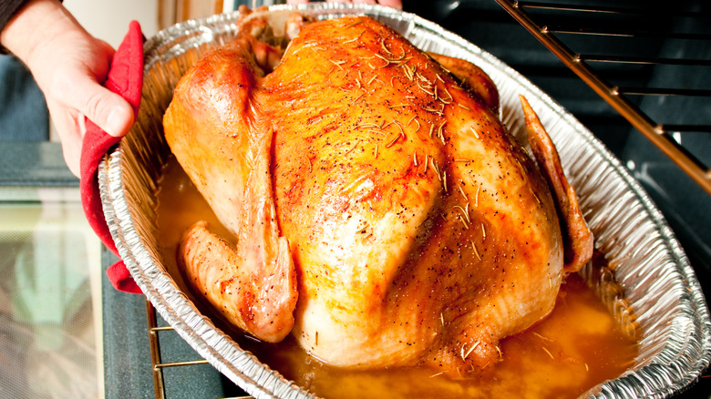 roast tukey in foil baking pan coming out the oven