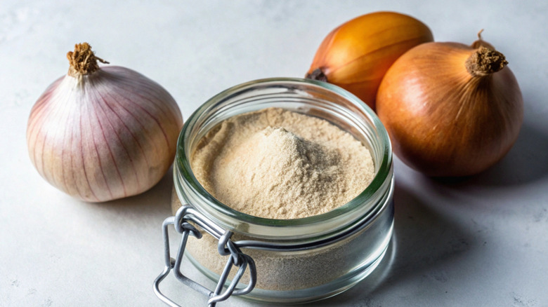 open jar of onion powder with fresh onions next to it