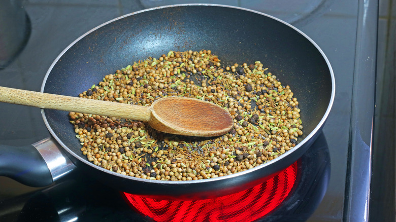 dry spices toasting on a pan on the stove