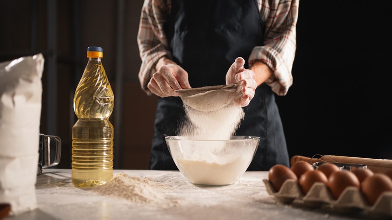 hands sifting flour into bowl