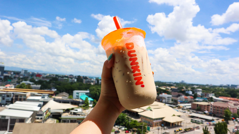 Person holding cup of Dunkin' iced coffee to the sky