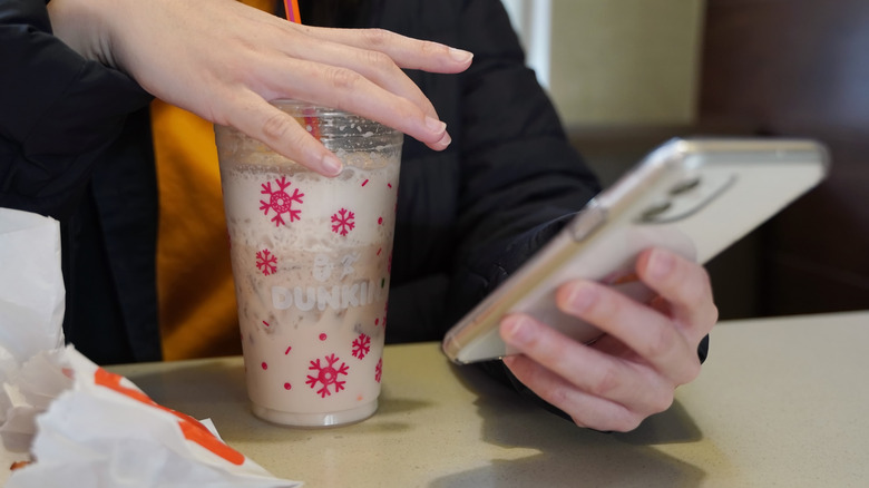 Person holding onto cup of Dunkin' holiday iced coffee while on phone