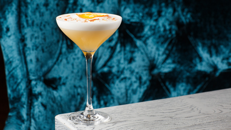 A frothy egg white cocktail in an elegant glass