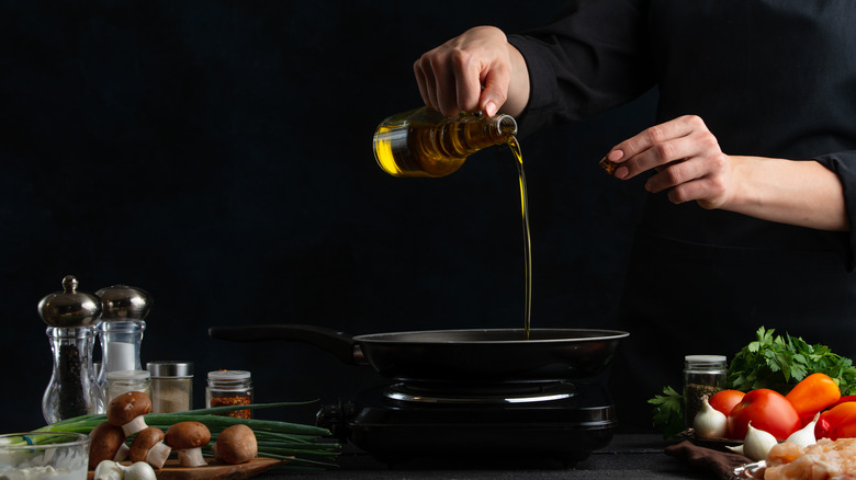 chef pours oil into drying pan