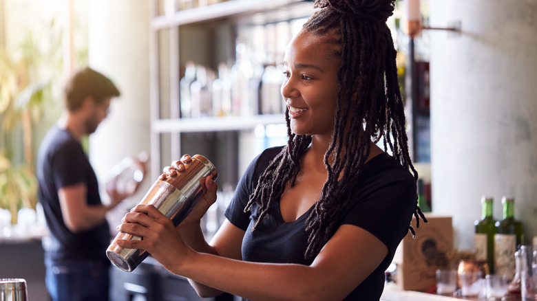 a young female bartender shaking a cocktail in a bar