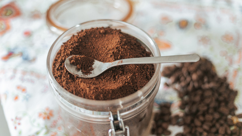 an open jar of ground coffee with a spoon on top