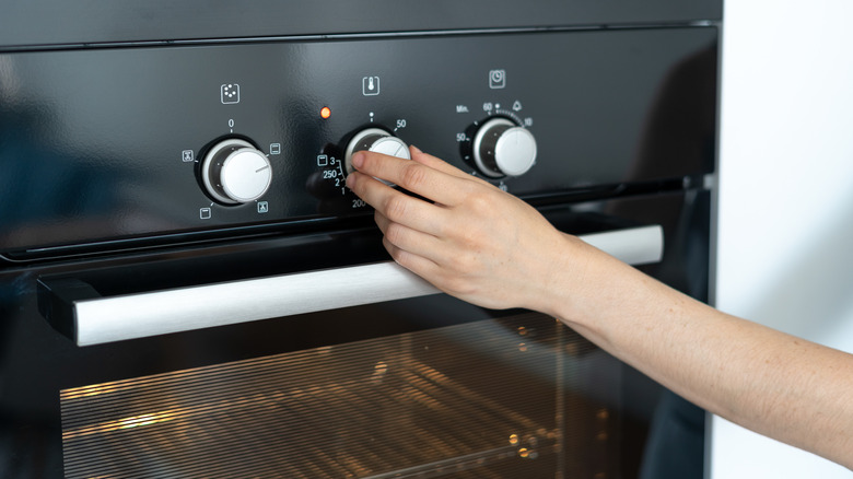 Hand adjusting oven temperature dial