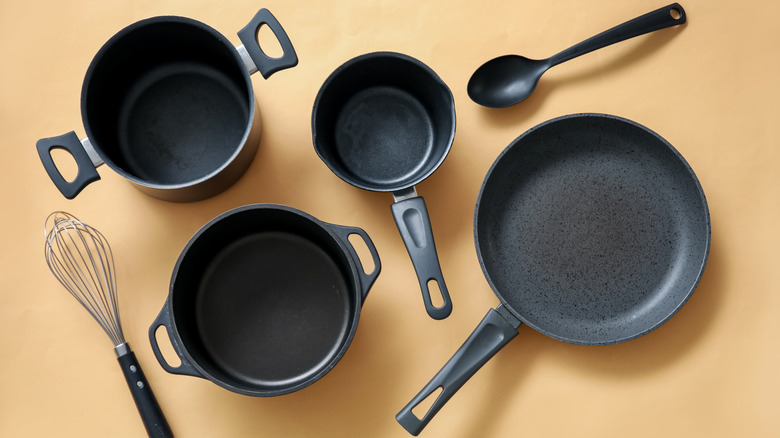 Cooking pots, frying pan and kitchen utensils on beige background