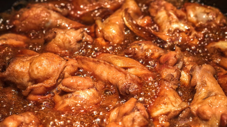 chicken wings simmering in a bubbling brown sauce