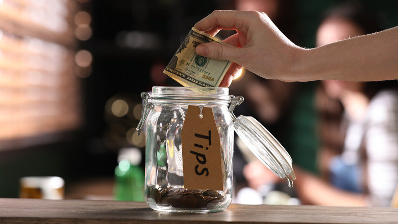 woman adding money in tipjar