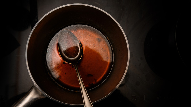 a spoon in a saucepan containing a sauce reduction