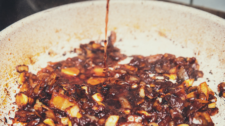 a close up of bourbon being used to deglaze a hot pan