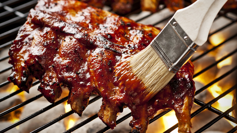 ribs on a barbeque being brushed with bourbon sauce