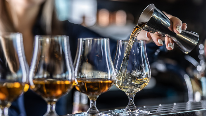 a bartender pouring bourbon into tasting glasses