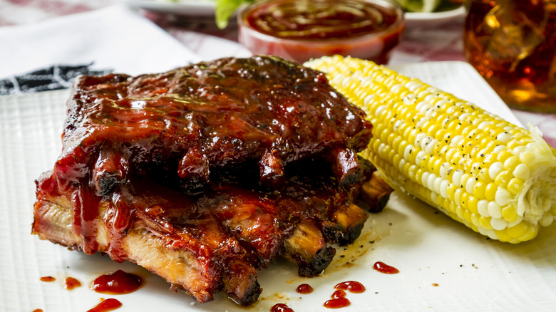 ribs covered with bourbon sauce next to corn on the cob