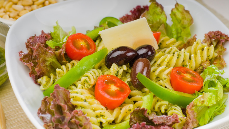 Pasta salad with pesto in white bowl