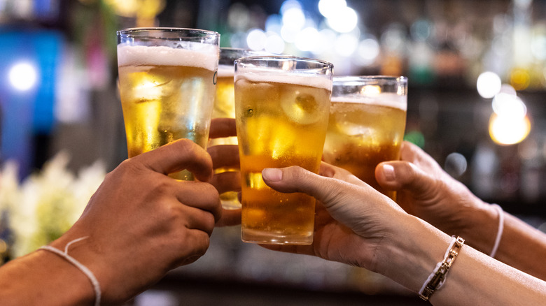 people clinking pints of lagers