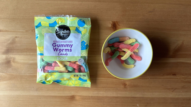 Signature Select Sour Gummy Worms bag with bowl on wooden table