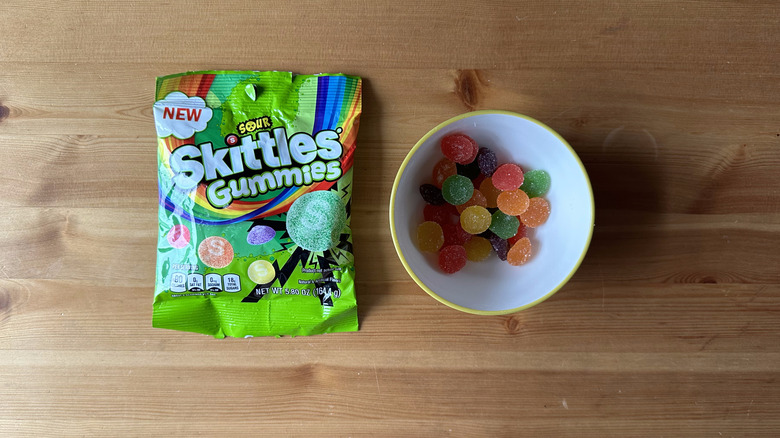 Sour Skittles Gummies bag with bowl on wooden table