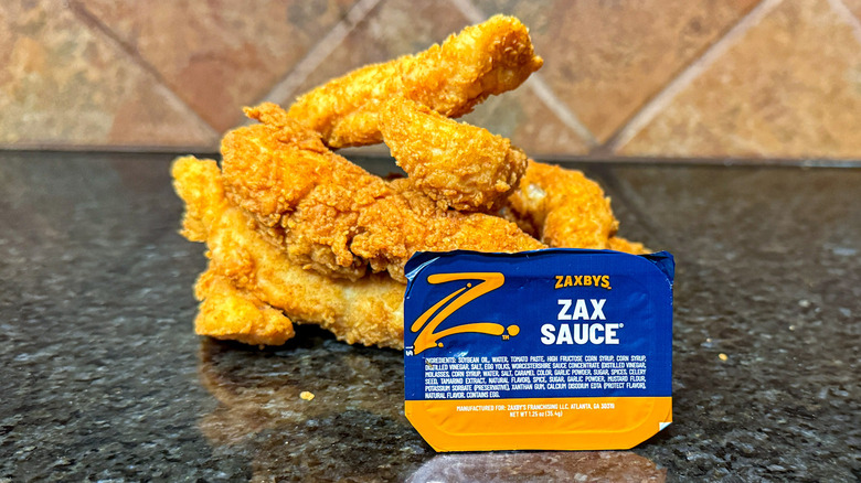 Pile of Zaxby's chicken tenders and container of Zax Sauce