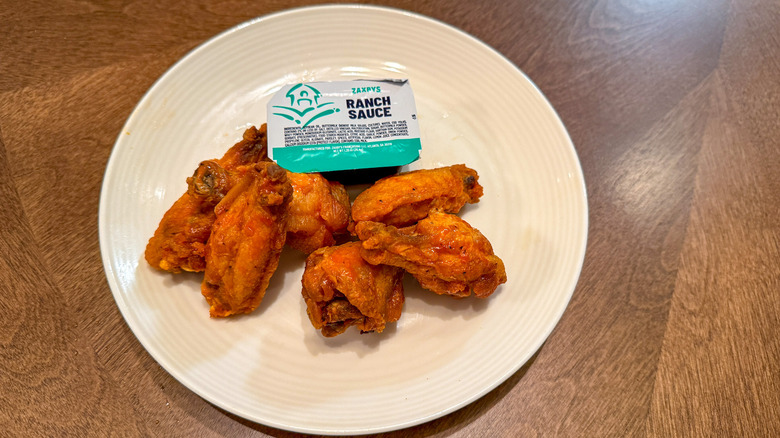 Six buffalo wings on a white plate