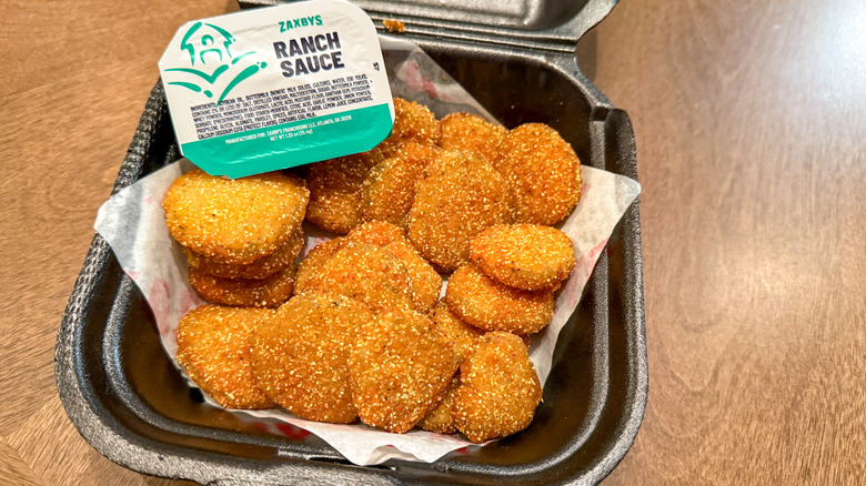 Fried pickle slices in a black takeout container