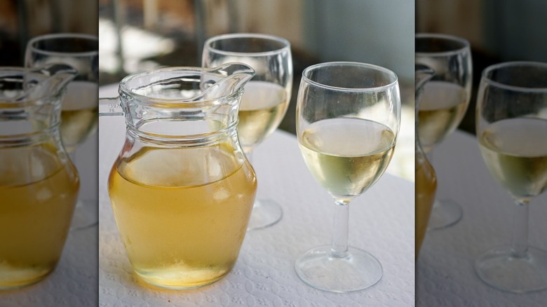Jug of white wine next to two glasses of wine 