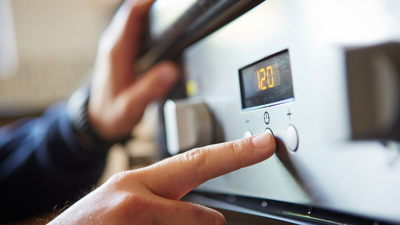 Hand pressing button on oven