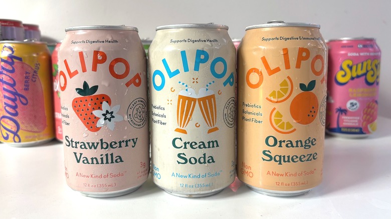 Three Olipop soda cans lined up on white table