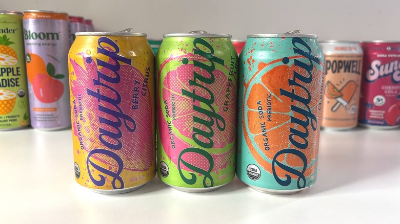 Three Daytrip soda cans lined up on white table