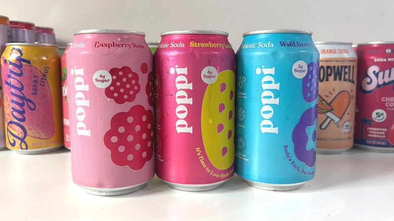 Three Poppi soda cans lined up on white table