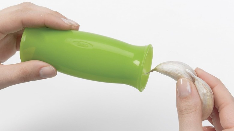A person putting a garlic clove into an OXO peeler
