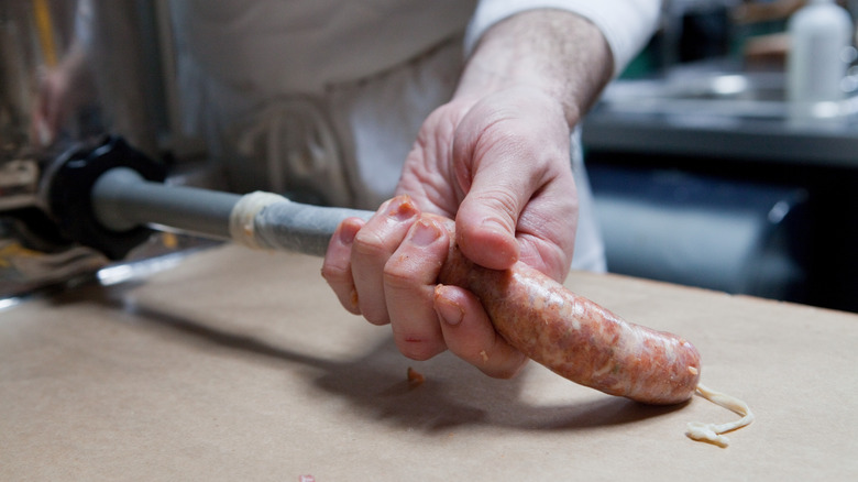 Butcher encasing sausage with machine