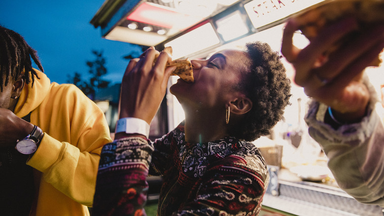 woman eating pizza at a festival