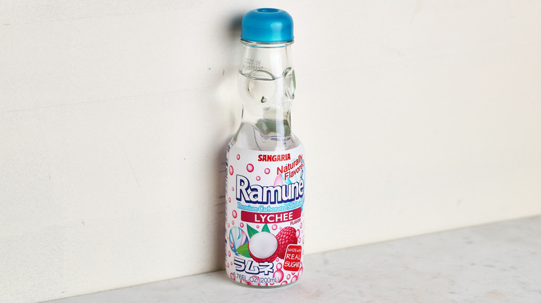 Glass bottle of Ramune lychee soda sitting on a table